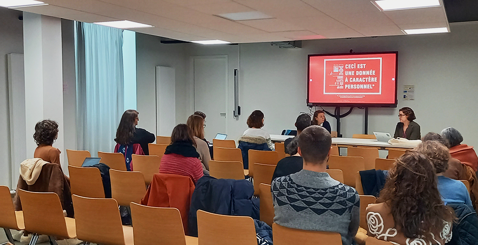 Photographie de l'action de sensibilisation des agents de la métropole de Nantes. Dans une salle, un agent de la CNIL, face caméra, présente des diapositives à un public photographié de dos.