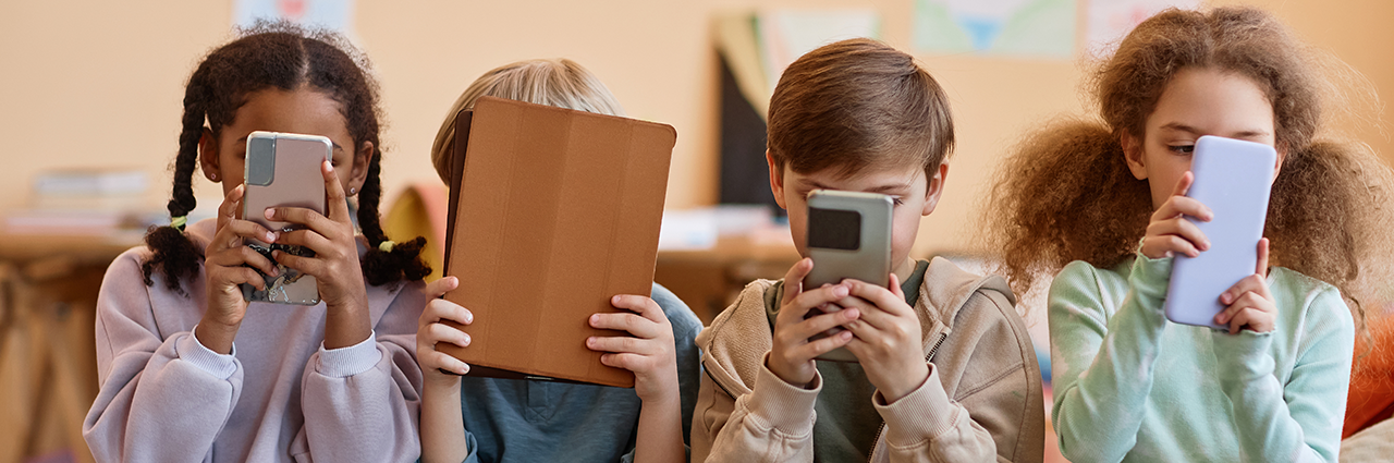 Vue de face d'enfants sur des tablettes et téléphones