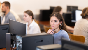 Photographie d'élèves devant des ordinateurs dans une salle de cours en faculté