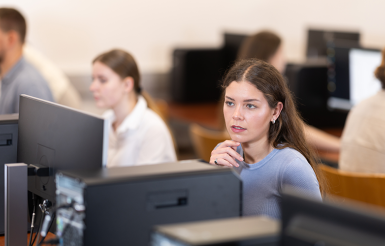 Photographie d'élèves devant des ordinateurs dans une salle de cours en faculté